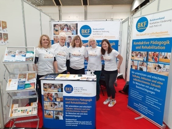 Fünf Personen in weißen T-Shirts am BKF Messestand Logo BKF Bundesverband Konduktive Förderung nach Petö e.V.